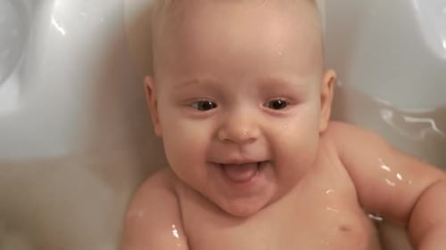 Smiling Fair Haired Baby Enjoying a Bath