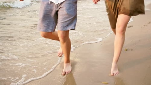 Couple Runs Barefoot on Beach at Sunset