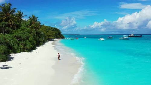 Pretty smiling girl on photoshoot enjoying life on the beach on clean white sand and blue 4K backgro