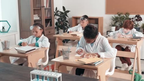Children in Lab Coats Writing Notes in Class