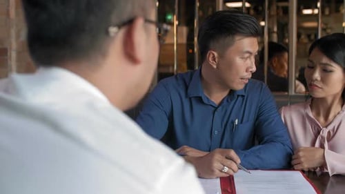 Couple Reviewing Contract with Professional in Office