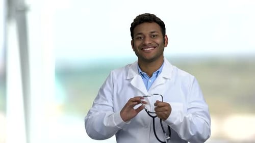 Young Dark-skinned Doctor Puts on Stethoscope.