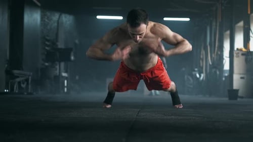Athlete with a Beautiful Body and a Naked Torso Doing Push-ups Exercise on the Floor at the Gym