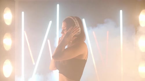 Energetic Woman Dancing with Headphones in Neon Lights
