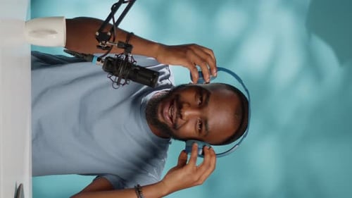 Man Puts On Headphones and Nods at Microphone