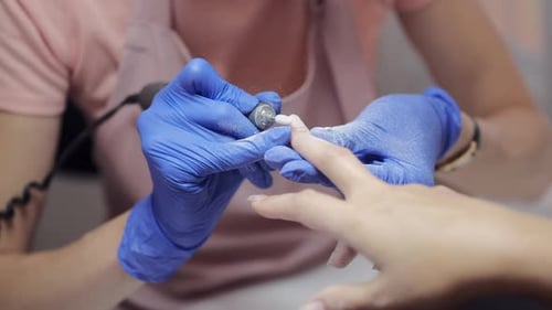 Manicure Master in Blue Gloves Polishes Client Nail in Salon