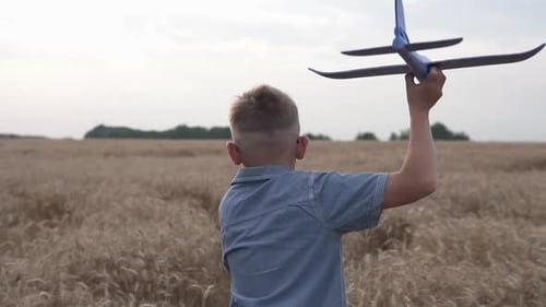 Happy guy with a toy airplane on a wheat field in the sunset light.
