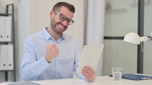 Man Excitedly Video Conferencing Using Tablet at Desk