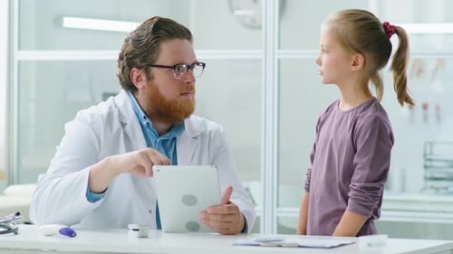 Doctor and Little Girl Using Tablet in Medical Office