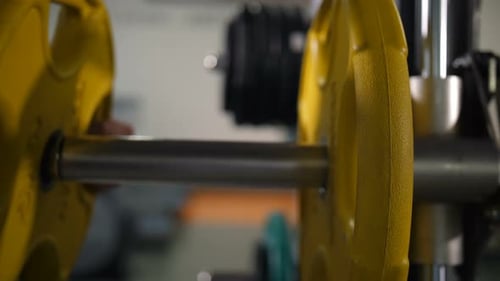 Person adds yellow weights to a barbell