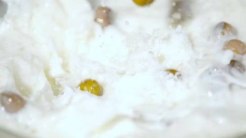 Extreme close up of hazelnuts falling into milk, Ultra Slow Motion