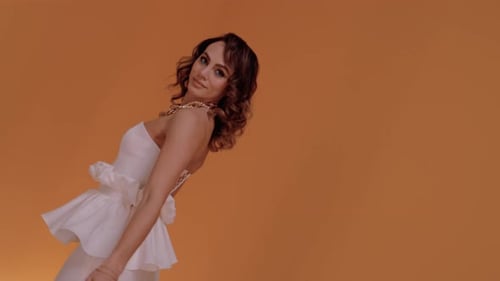 Stylish Woman Poses on Orange Background