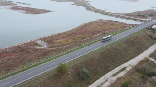 Luftaufnahme eines Busses, der entlang einer Autobahn neben der Küste eines Sees fährt.