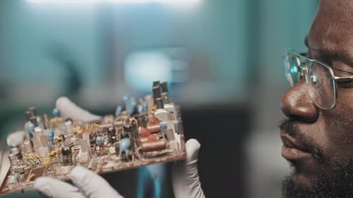 Black Engineer Examining Circuit Board