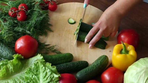 Close-up of Cook Cutting Fresh Cucumber on Wooden Chopping Board.