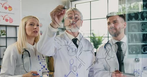 Un médecin principal barbu et mature écrit une formule chimique sur un mur