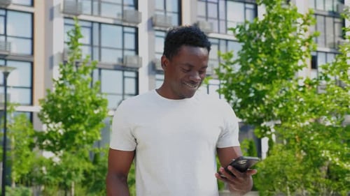 Man Uses Phone and Drinks Coffee Outdoors