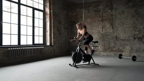 Young active woman relax on bike in gym. Female training on bike