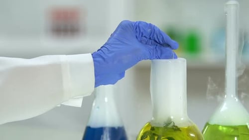 Lab Assistant Taking Sample of Boiling Plant Liquid and Pouring Into Test Tube