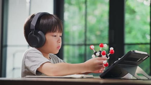 Asian little boy assembling molecular model by learning from home with school teacher in house.