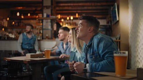 Friends are Watching Together Emotionally Watching Football on TV in a Bar and Celebrating the