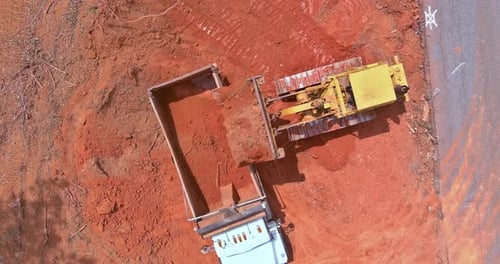 Bulldozer Loading Red Soil into Truck from Above