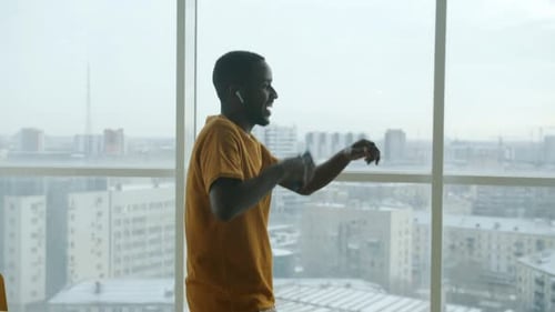 Cheerful Man Dances to Music with City View