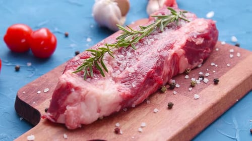 Raw Steak with Rosemary on Cutting Board