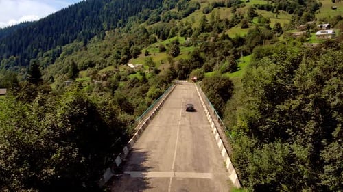 Car Driving on Alpine Road on Mountains Background