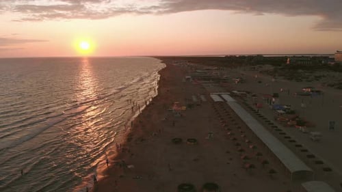 Aerial View of Beautiful Sunset Over Sea and Sand Beach, People Are Swimming in the Waves