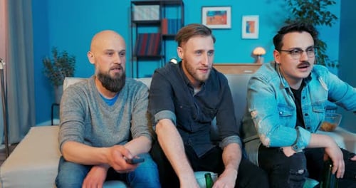 Group of Buddies Sitting on Sofa in Living Room Evening with Beer in Hand Front