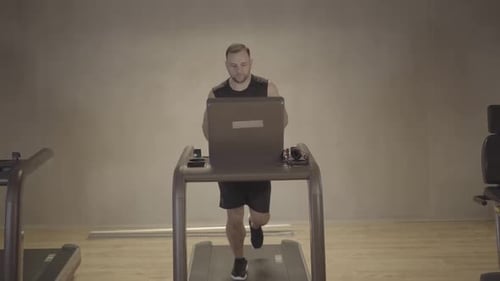 Wide Shot of Serious Sportsman Running on Treadmill in Gym. Front View Portrait of Caucasian