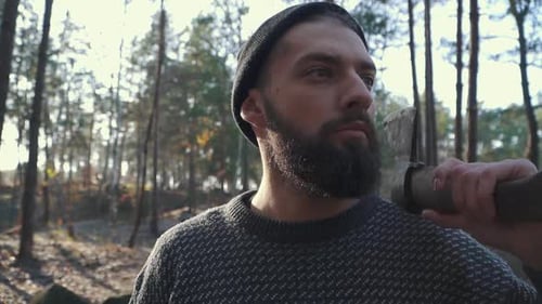 Bärtiger Mann mit einer Axt auf der Schulter, der weit nach vorne schaut