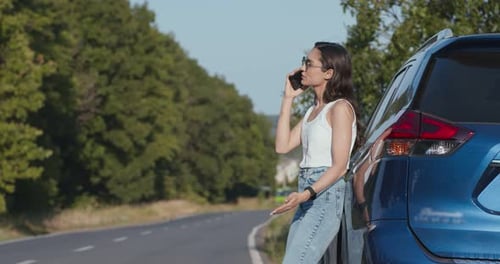 Woman Talking on Phone by Blue Car on Road