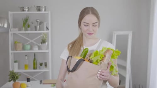 Middle Shot of Young Pretty Girl Posing with Grocery Bag at Home