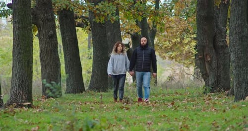 Happy Young Couple in the Autumn Forest Walks Along the Paths
