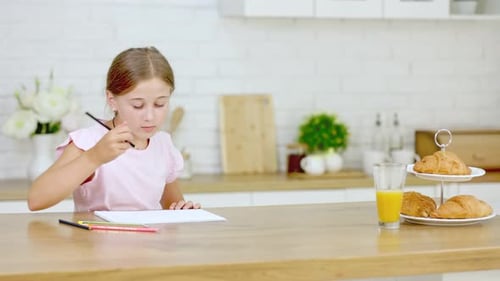 Happy Child Drawing at Kitchen Table with Breakfast