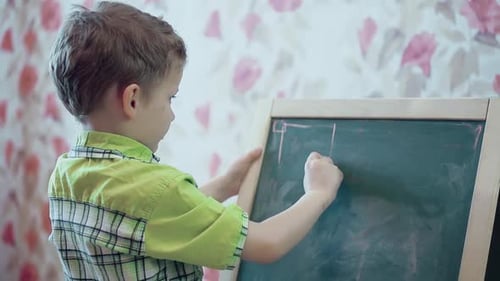 Little Boy Drawing on a Chalkboard