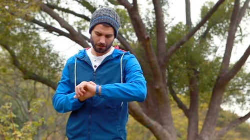 Bearded Man Checks Watch in Park in Fall