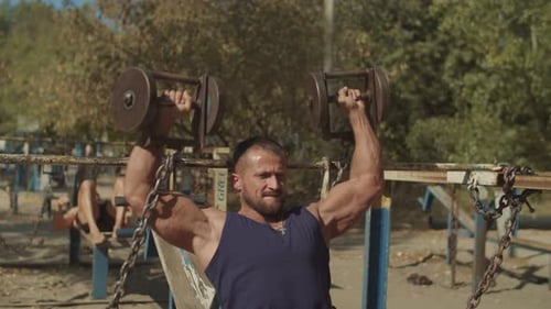 Muscular Man Lifting Weights at Outdoor Gym