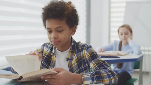 Student Reads Book and Smiles in Classroom
