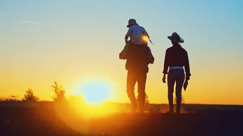 Silhouette of Familychild is Sitting on Dad Shoulders and Mom Walking Next on Summer Evening at