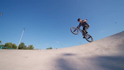 Young Adult Performing Bicycle Stunts in Skatepark