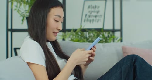 Young Woman Using Smartphone on Couch Indoors