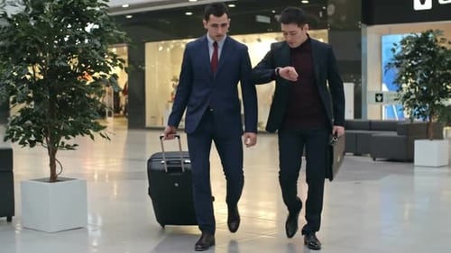 Two Men Walking with Suitcase in Urban Mall