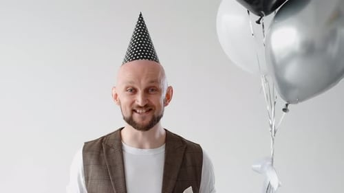 Cheerful Man Celebrating Birthday with Balloons and Blower