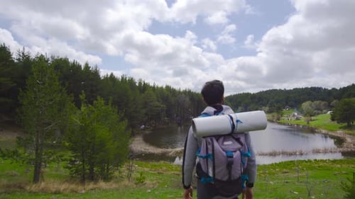Hiker with Backpack Near Scenic Forest Lake