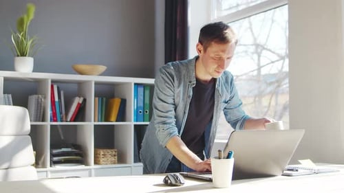 Young male entrepreneur works at home office at the computer.