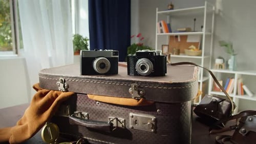 Vintage Cameras and Suitcase on Table Indoors