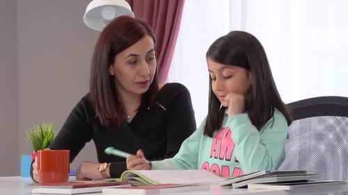 Woman Helps Girl With Homework Indoors During Day